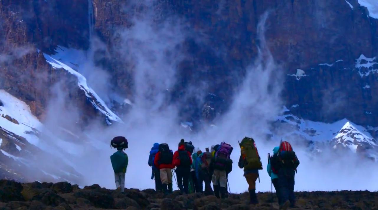 Climbers walking toward a wall of mist and snow on Kilimanjaro