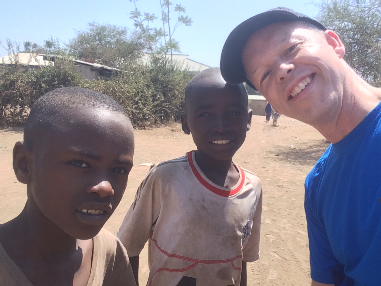 Two boys outside their village on a bright afternoon
