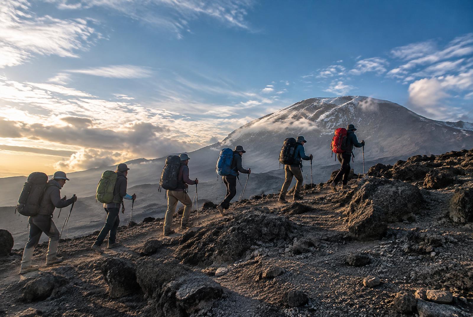 Trekkers ascending a rocky ridge on Mount Kilimanjaro at first light